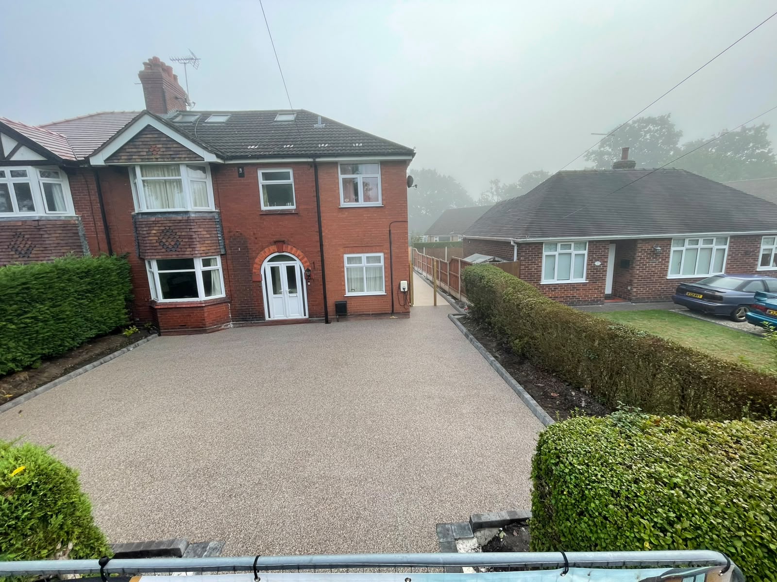 Light-coloured resin-bound driveway outside a red-brick house in Elworth, with grey kerb edging and a white car